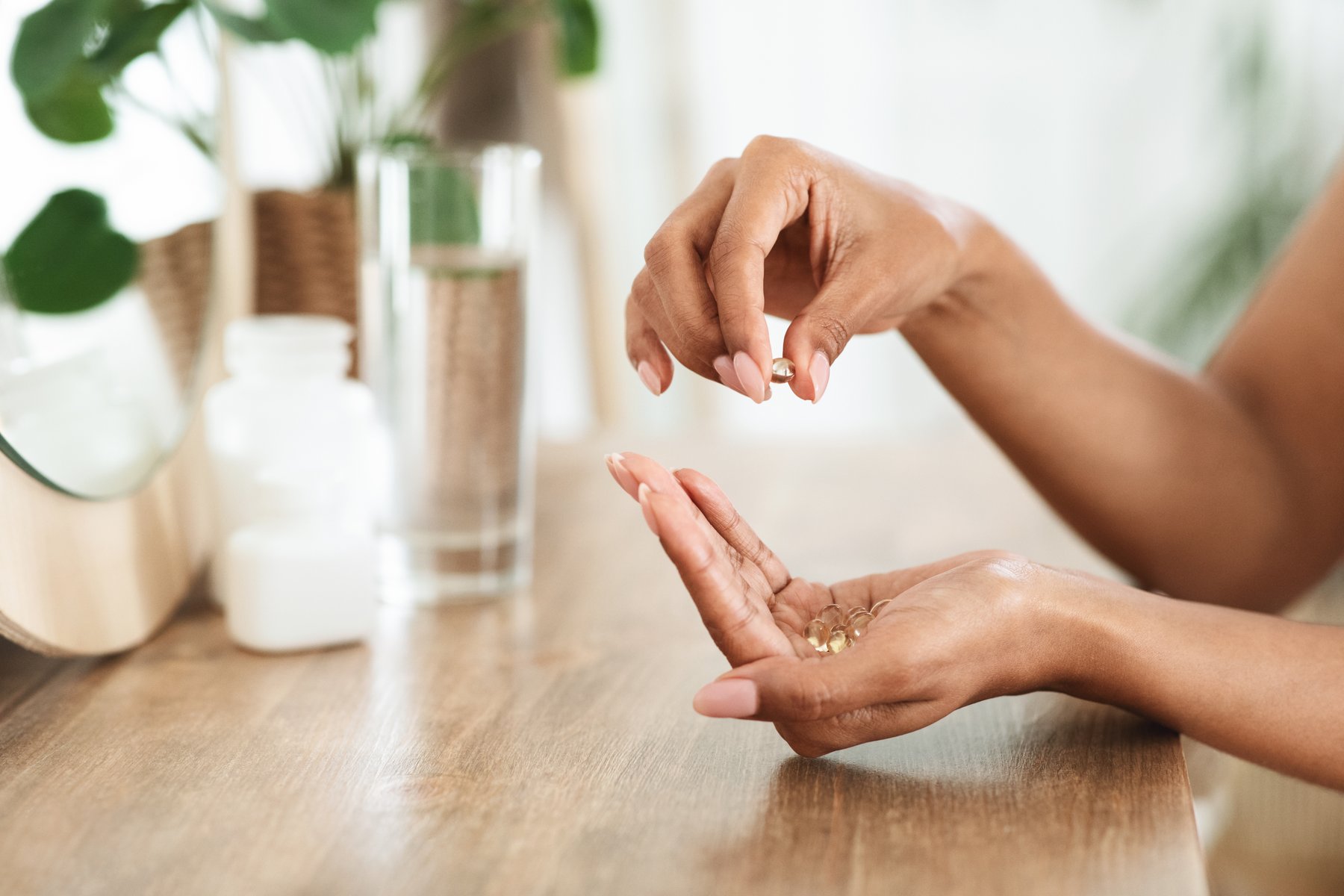 Professional-grade supplement capsules and a glass of water on a beige background